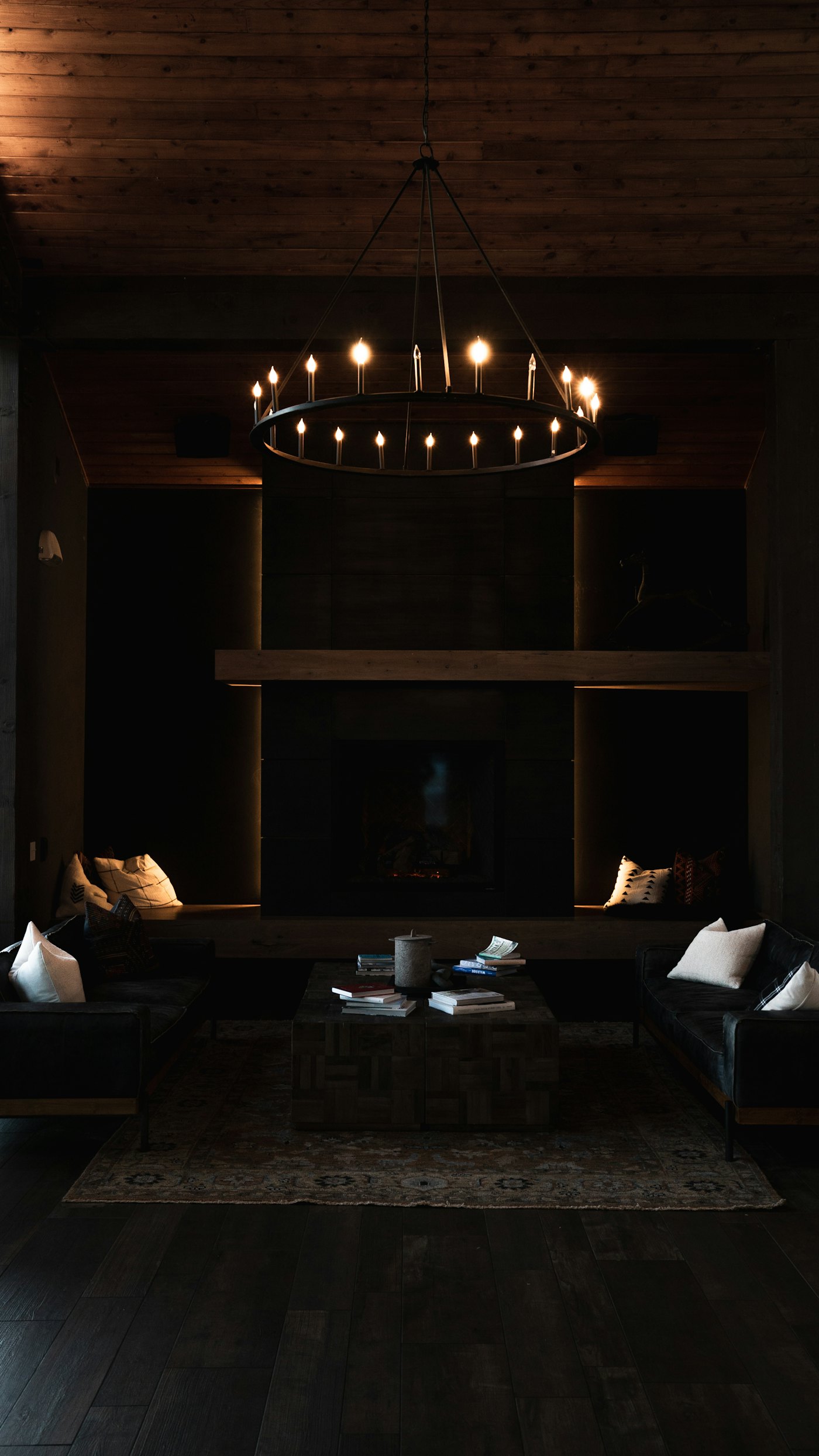 Sala à noite com lustre e luz indireta (cove) valorizando a lareira